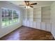 Home office featuring built-in shelving and cabinets, hardwood floors, and a large window with a peaceful view at 1000 High Brook Dr, Waxhaw, NC 28173