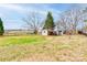 Spacious backyard featuring a mix of grassy areas, mature trees, and multiple outbuildings at 107 Destiny Ln, Shelby, NC 28150