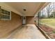 Cozy carport featuring a concrete floor, brick pillars, a white paneled door, and a manicured lawn leading to the wooded area at 117 Gwyn St, Wingate, NC 28174