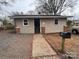 Simple tan home featuring gravel front yard, brick accents, and black mailbox at 1224 Hollywood Ter, Albemarle, NC 28001