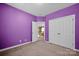 Purple bedroom with carpet, featuring a closet and access to the landing area and stairs at 14333 Maclauren Ln, Huntersville, NC 28078