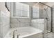 An elegant bathroom with a soaking tub, a glass shower, and marble tile at 3193 Burnello Ct, Iron Station, NC 28080