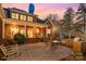 Back of the house at dusk showcasing the spacious patio, grill, and covered porch with illuminated windows at 4421 Windwood Cir, Charlotte, NC 28226