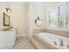 Bathroom features a soaking tub with tiled surround, a vanity with sink and a window with shutters at 4421 Windwood Cir, Charlotte, NC 28226
