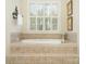 Relaxing bathroom showcases a luxurious bathtub with tile surround, a large window and shuttered blinds at 4421 Windwood Cir, Charlotte, NC 28226