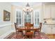 Elegant dining room featuring a chandelier, round wooden table, and large windows with shutters at 4421 Windwood Cir, Charlotte, NC 28226