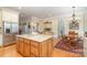 Spacious eat-in kitchen with island, granite counters, stainless refrigerator and chandelier over the dining table at 4421 Windwood Cir, Charlotte, NC 28226