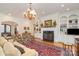 Charming living room with a fireplace, built-in bookshelves, hardwood floors, and ornate chandelier at 4421 Windwood Cir, Charlotte, NC 28226