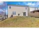 Backyard of a home featuring tan siding, sliding glass door, and a grassy hill at 4635 Christenbury Hills Ln, Charlotte, NC 28269