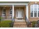 Inviting front porch with classic columns, rocking chairs, and brick stairs with black iron railings at 561 Keystone Nw Ct, Concord, NC 28027