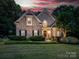 Charming two-story home with brick facade, manicured lawn, and mature landscaping with warm sunset lighting at 821 Lynnwood Farms Dr, Fort Mill, SC 29715