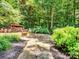 Stone patio with fire pit area, surrounded by lush greenery and mulch beds, offering a cozy outdoor space at 821 Lynnwood Farms Dr, Fort Mill, SC 29715