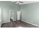 Bedroom with gray walls, wood-look floors, ceiling fan, and doorway to the en-suite bathroom at 8421 Kings Creek Dr, Charlotte, NC 28273