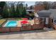 Aerial view of backyard pool area with umbrellas, brick fencing, and lush landscaping at 104 N Hawthorne St, Mount Holly, NC 28120