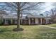 Brick home features a covered porch, and a mature tree in the front yard at 104 N Hawthorne St, Mount Holly, NC 28120