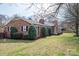 A brick home with a covered front porch, black shutters, and landscaping with manicured shrubs at 104 N Hawthorne St, Mount Holly, NC 28120