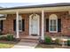 The front porch offers an inviting entrance with brick detailing, columns, and stylish outdoor lighting at 104 N Hawthorne St, Mount Holly, NC 28120