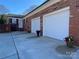 A brick home featuring a spacious driveway leading to a two-car garage with white doors and beautiful flower pots at 104 N Hawthorne St, Mount Holly, NC 28120