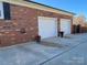 Home with two-car garage with white garage doors and a spacious driveway, brick siding, and decorative flower pots at 104 N Hawthorne St, Mount Holly, NC 28120