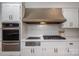 Close up of the modern kitchen featuring stainless appliances, hood vent, gas cooktop and custom cabinetry at 104 N Hawthorne St, Mount Holly, NC 28120