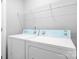 Bright laundry room with white appliances including a washer, a dryer, and white wire shelving at 12417 Mcgrath Dr, Charlotte, NC 28269