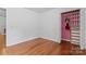 Bright bedroom features hardwood floors and closet with custom organizers and pink striped wallpaper at 1347 Eisenhower Nw Pl, Concord, NC 28027
