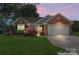 Charming single-story home with brick accents, manicured lawn, and a two-car garage, set against a beautiful dusk sky at 1347 Eisenhower Nw Pl, Concord, NC 28027