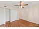 Bedroom featuring neutral walls, wood floors, ceiling fan, closet, and white trim at 1606 Eagles Pl # J101, Rock Hill, SC 29732