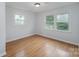 This bright bedroom features gleaming hardwood floors and a large window at 16308 Poplar Tent Rd, Huntersville, NC 28078
