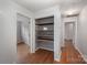 Hallway with hardwood floors and open shelving for storage or display, connecting to various rooms at 16308 Poplar Tent Rd, Huntersville, NC 28078