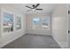 Bright, neutral bedroom featuring carpeting, a modern ceiling fan, and two large windows at 201 Pleasant Ave, Stanfield, NC 28163