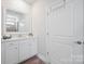 Clean bathroom featuring a white vanity, large mirror, and white door at 22014 Finworthy Ln, Huntersville, NC 28078