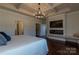 Cozy main bedroom with fireplace, tray ceiling, chandelier, and access to an ensuite bathroom at 246 Sweet Briar Dr, Fort Mill, SC 29707