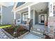 Inviting covered front porch with rocking chairs, stone accents, and landscaped garden bed at 4315 Innisfree Ct, Indian Trail, NC 28079