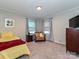 Relaxing bedroom with yellow bedding, a side table, cozy chair, and natural light from two windows at 464 Willetta Nw Pl, Concord, NC 28027