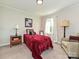Comfortable bedroom with a red bedspread, a bedside table with a lamp, and a cozy chair at 464 Willetta Nw Pl, Concord, NC 28027