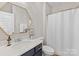 Bathroom featuring a marble countertop, blue vanity, a decorative mirror, and shower with a white curtain at 5013 Watercrest Trl, Belmont, NC 28012
