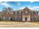 Stately brick home with black shutters, a manicured lawn, and a circular window above the entry adds architectural interest at 725 Stanhope Ln, Matthews, NC 28105