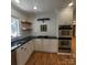 Updated kitchen with white cabinets, stainless steel appliances, floating wood shelves, and hardwood floors at 1003 Woodland Dr, Gastonia, NC 28054