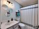 Cozy bathroom featuring a toilet and shower/tub with decorative shower curtain, complimented by vanity and circular mirrors at 1022 Mallard Head Ln, Mooresville, NC 28117