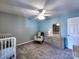 Light filled bedroom featuring a ceiling fan, neutral walls, plush carpet, a rocking chair, dresser and crib at 1022 Mallard Head Ln, Mooresville, NC 28117