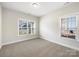 Well-lit bedroom showcasing neutral carpet, base trim, and two windows for ample natural light at 1063 Millview Ln, Matthews, NC 28104