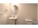A clean, minimalist powder room featuring a pedestal sink and a round mirror at 12128 Lady Bell Dr, Charlotte, NC 28278