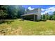 View of the grassy backyard featuring an open porch, mature trees, and green lawn at 1298 Hines Rd, Clover, SC 29710
