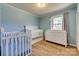 Bedroom with blue walls, two white cribs, and a white dresser with changing table at 2027 Franklin St, Rock Hill, SC 29732