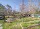 Spacious backyard featuring lush grass, mature trees, a fire pit, and various sheds and garden beds at 2036 Edgewater Dr, Charlotte, NC 28210
