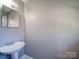 Bathroom featuring pedestal sink, mirror, light gray walls, and updated fixtures at 2036 Edgewater Dr, Charlotte, NC 28210