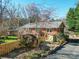 Charming red brick home featuring a rock surrounded by a wooden fence and beautiful landscaping at 2036 Edgewater Dr, Charlotte, NC 28210