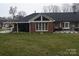 Backyard features a well-maintained lawn, a brick home with large windows, and a covered patio area at 2207 Windsor Woods Dr, Gastonia, NC 28054