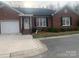 Charming brick home featuring a one-car garage and a cozy front porch entrance, providing a welcoming curb appeal at 2207 Windsor Woods Dr, Gastonia, NC 28054